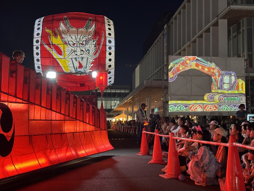 本物のあんどん山車の隣で、来場者の写真から生成された山車をスクリーンに投影している様子